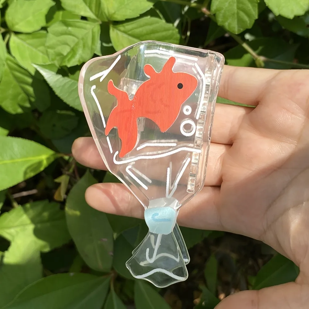 تصميم لخزان الأسماك الشفافة على شكل سمكة ذهبية، تصميم ممتع لخزان الأسماك باللون البرتقالي والأزرق، مناسب لتصفيف الشعر غير الرسمي