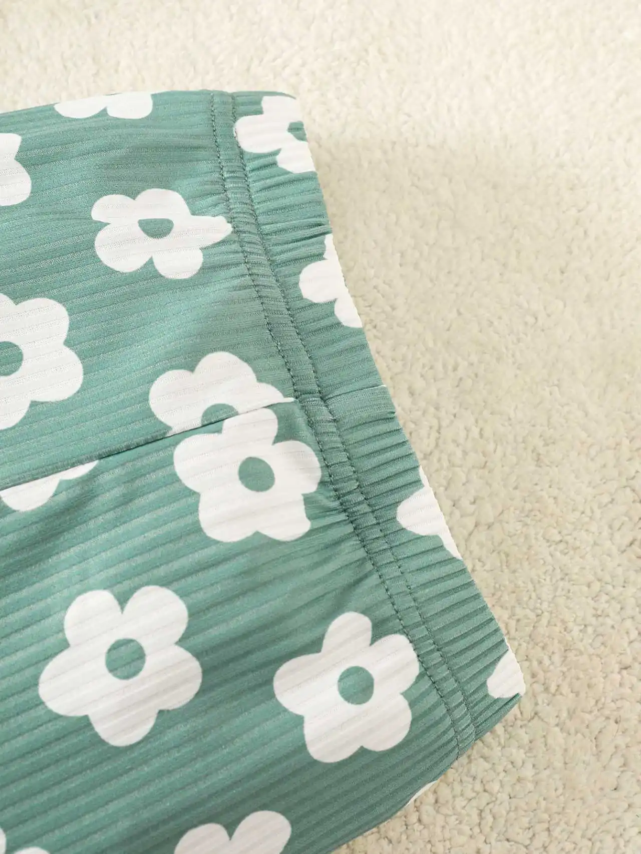 Grünes Set aus langärmligem Strampler mit Rundhalsausschnitt und kleinem Blumenmuster sowie einer langärmligen Stramplerhose mit süßem Blumenmuster für Babys. – Detail 5