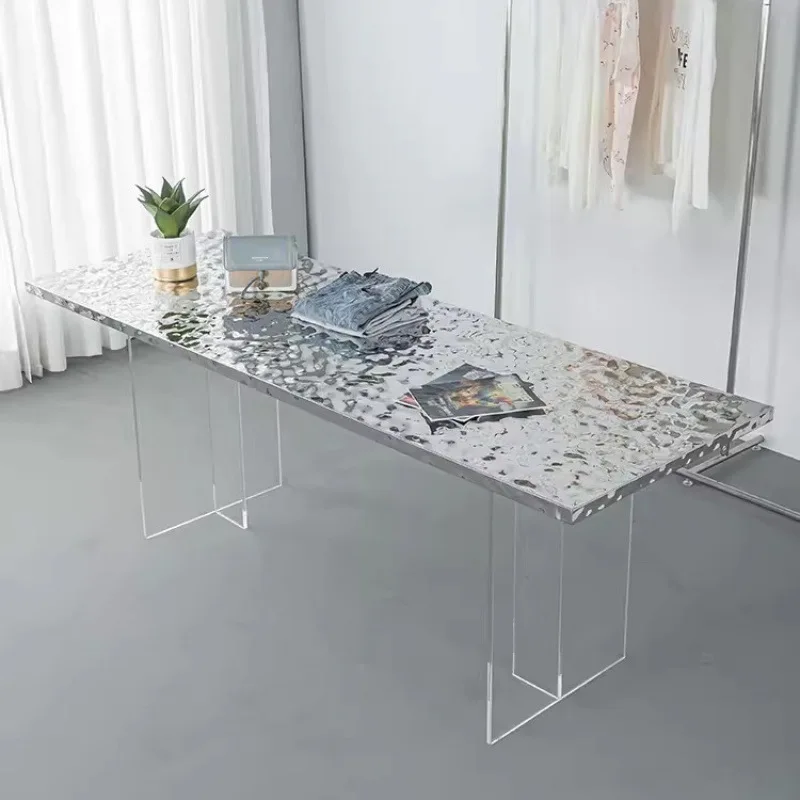 The island display table in the clothing store is placed in the middle of the flowing table