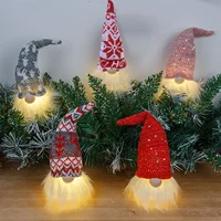 Set of glowing Christmas gnome decorations with knitted hats and warm LED beards in festive colours