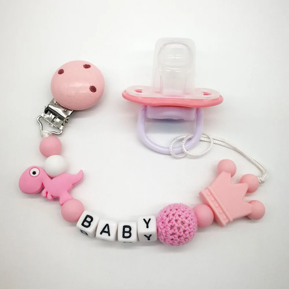 Drewniany łańcuszek do smoczka z motywem dinozaurów na prezent na baby shower