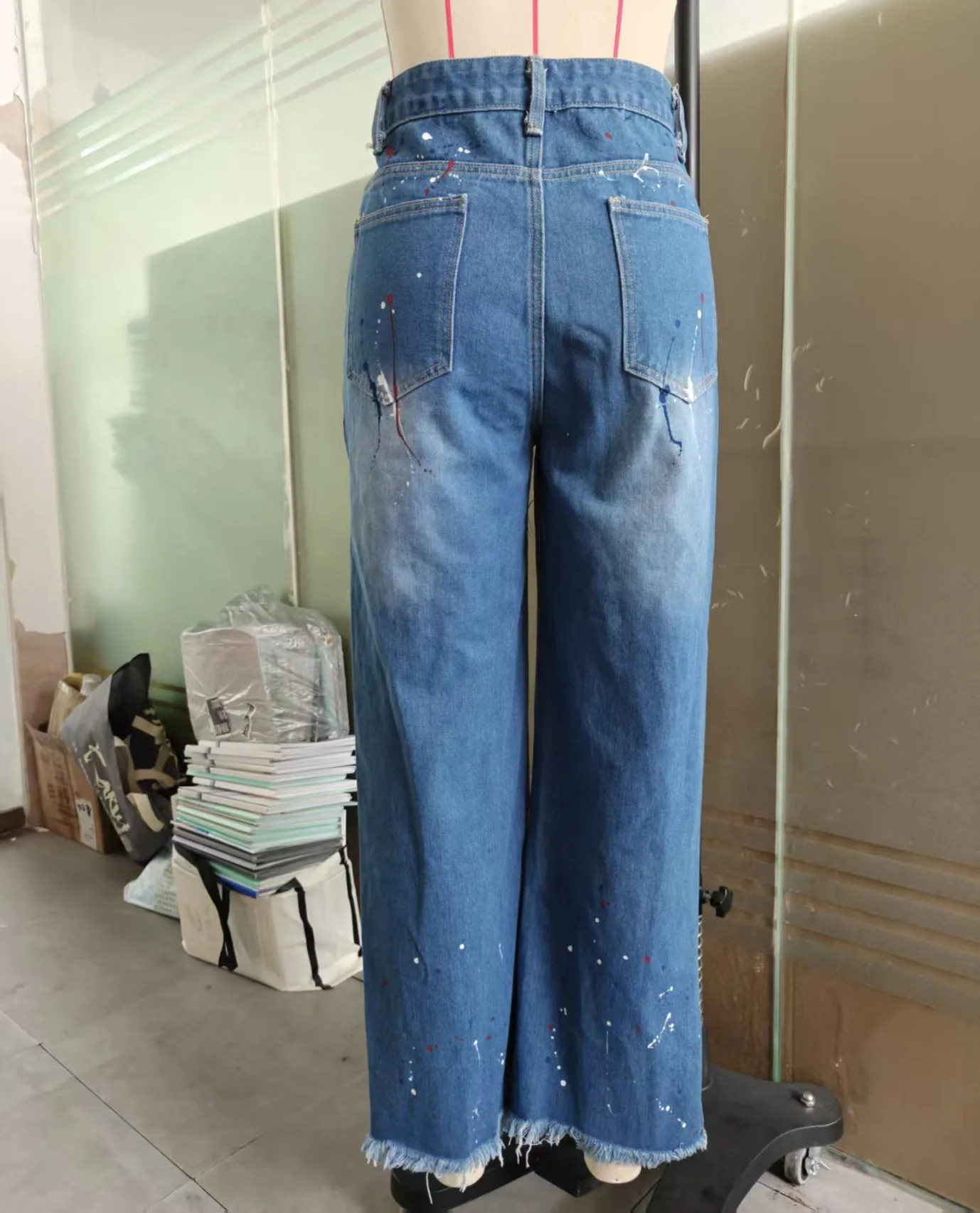 Celana jeans lurus robek dengan motif grafiti yang individual dan modis.