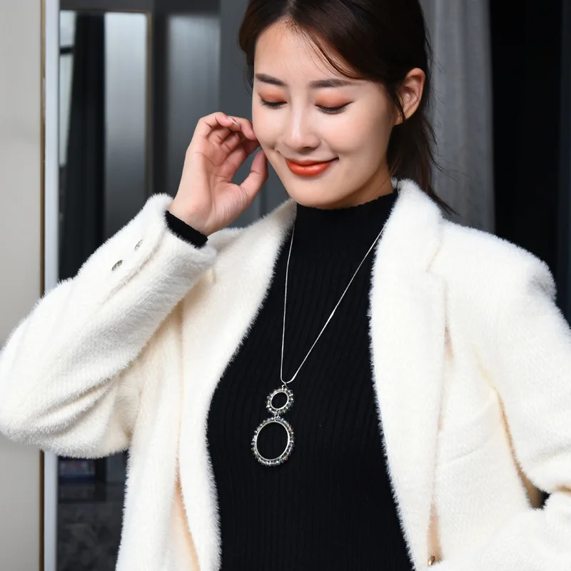 Una semplice nuova collana lunga a doppio anello, abbinata a una catena di maglioni di cristallo di diamanti nel cerchio della moda delle donne alla moda
