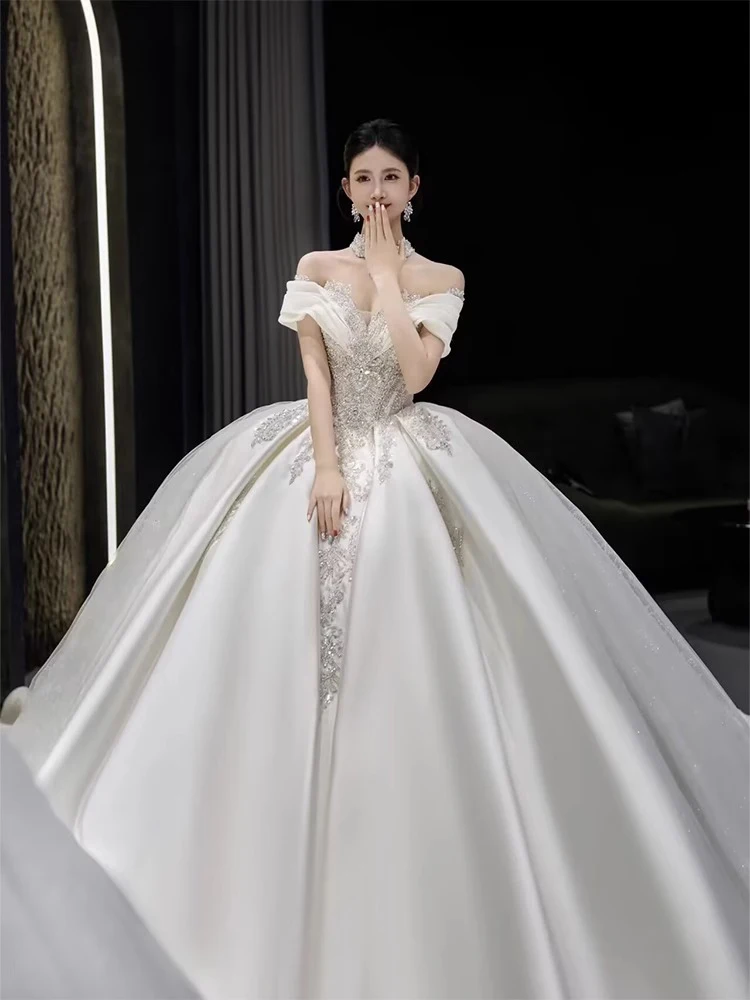 ชุดแต่งงานผ้าซาตินแบบไหล่เดียว ประดับตกแต่งอย่างหรูหรา พร้อมชายกระโปรงยาวแบบสเวปเทรน  ลายมัดย้อมแบบราชวงศ์  ประดับเพชรอะคริลิก  งานปักลายกลางตัวชุด