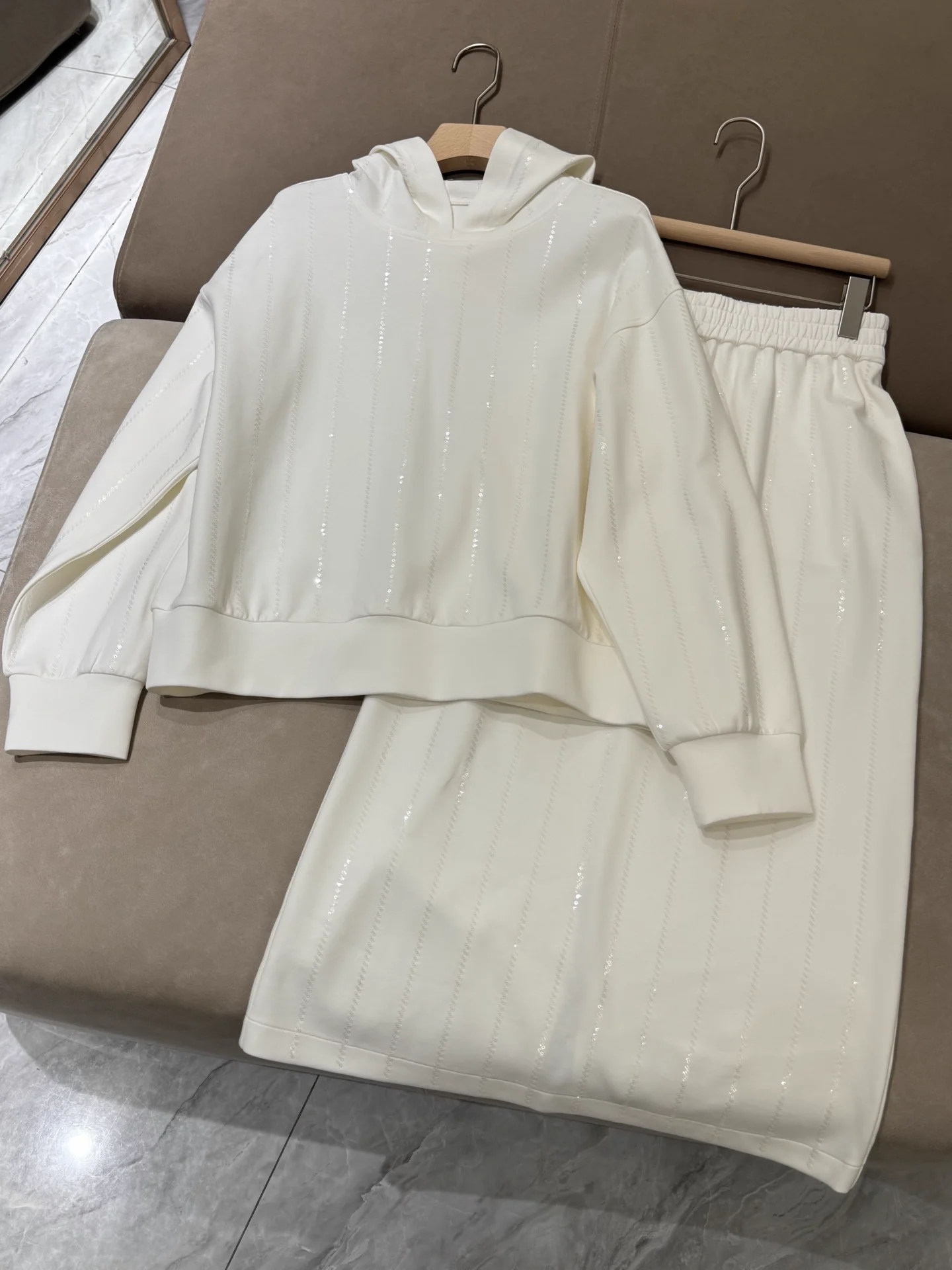 

Женский комплект из 3 предметов: юбка миди А-силуэта с эластичным поясом и пайетками + толстовка с капюшоном и длинными рукавами. Модный женский костюм.