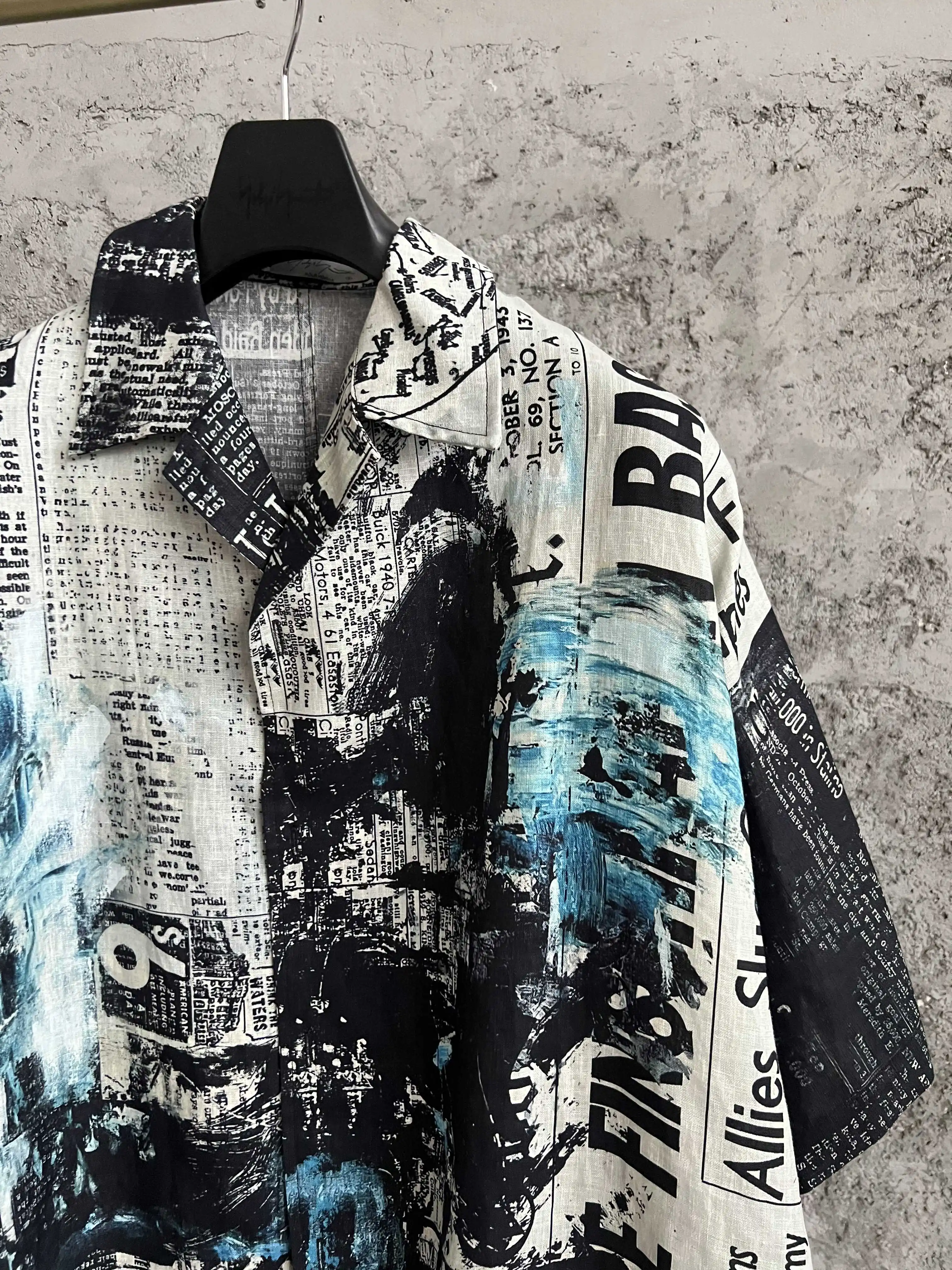 This all-cotton newspaper gun print short-sleeved open-collar shirt has a loose silhouette and is a niche men's three-quarter sl