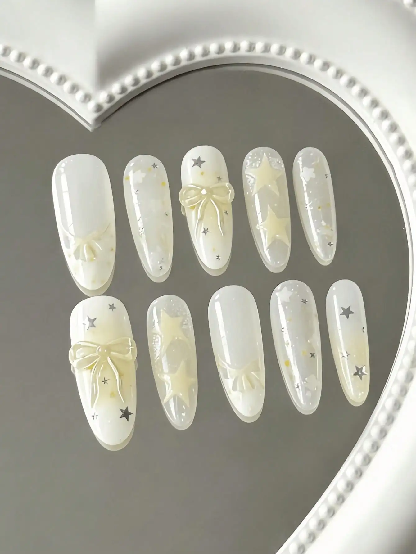 10 piezas de uñas postizas transparentes de longitud media en forma de almendra, en color amarillo cremoso con diseños de estrellas, con un estilo dulce y transparente, con lazos 3D, estrellas y patrones degradados, co