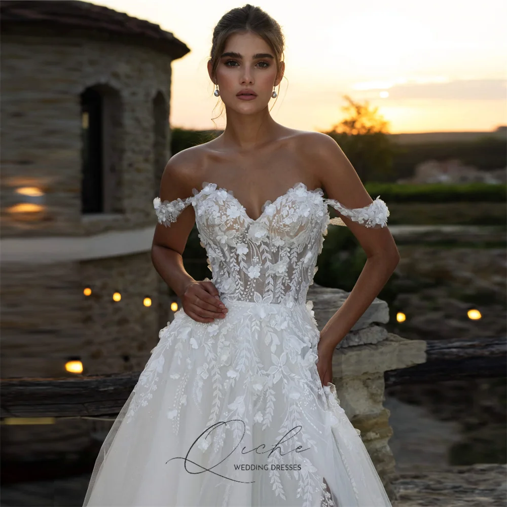 Elegancka suknia ślubna QICHE z aplikacjami z koronki, dekoltem w serek, krojem A-line, tiulowa, z odkrytymi ramionami, kwiatami 3D, rozcięciem, tiulowym odkrytym tyłem, możliwość personalizacji, kolekcja 2026.