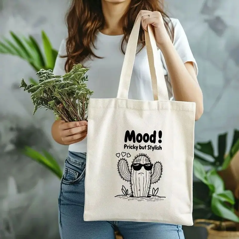 A black print“Mood! Pricky But Stylish”Text and cartoon cactus with glasses design，Light brown wooden surface style tote bag