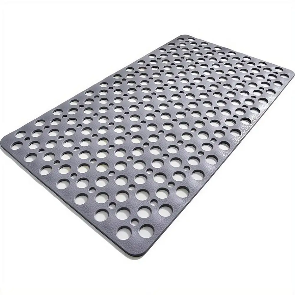 White bathroom mat with suction cups and drainage holes, placed on tiled shower floor.
