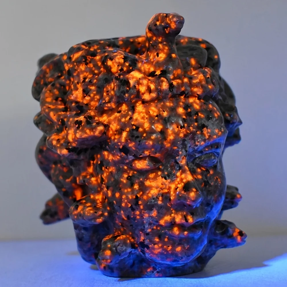 A handcrafted obsidian Medusa head with snake heads | Greek mythology decoration, shimmering gold under UV light， home decor