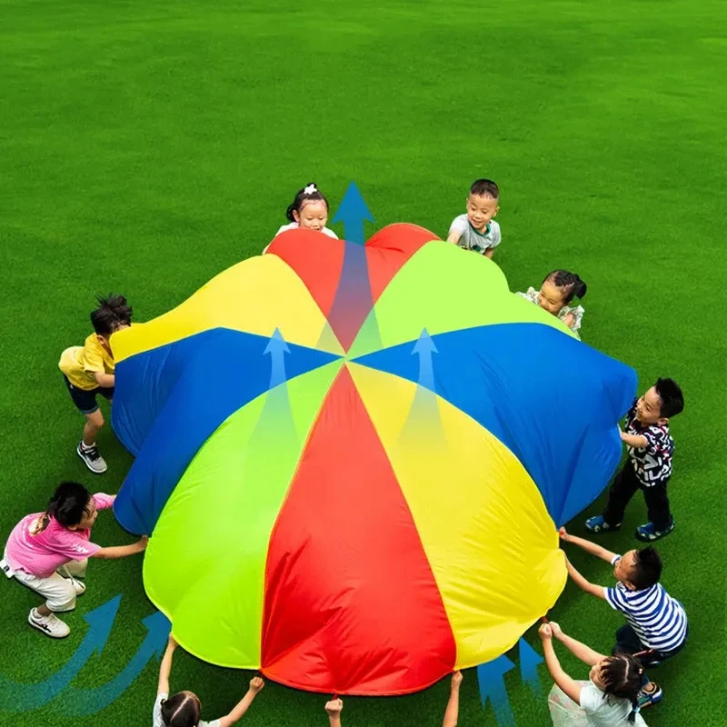 Várias pessoas acampamento ao ar livre arco-íris guarda-chuva pára-quedas brinquedo salto-saco ballute jogar interativo jogo de trabalho em equipe