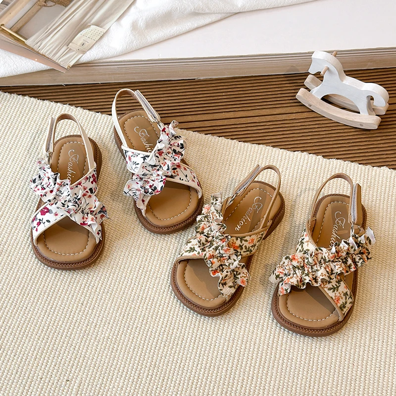 

Новые детские летние сандалии 2026 года для девочек: с цветочным принтом, рюшами, нескользящие, повседневные, с открытым носком, на плоской подошве