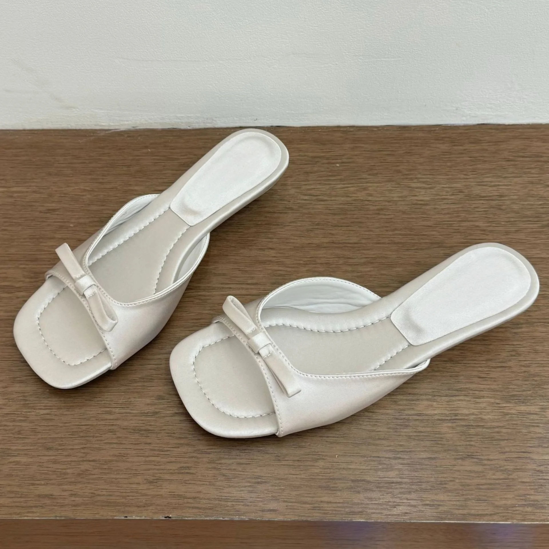 

Сандалии-шлепанцы на танкетке с открытым носком, с декоративным бантом-бабочкой, с неглубоким вырезом, квадратным носком, простые и элегантные.