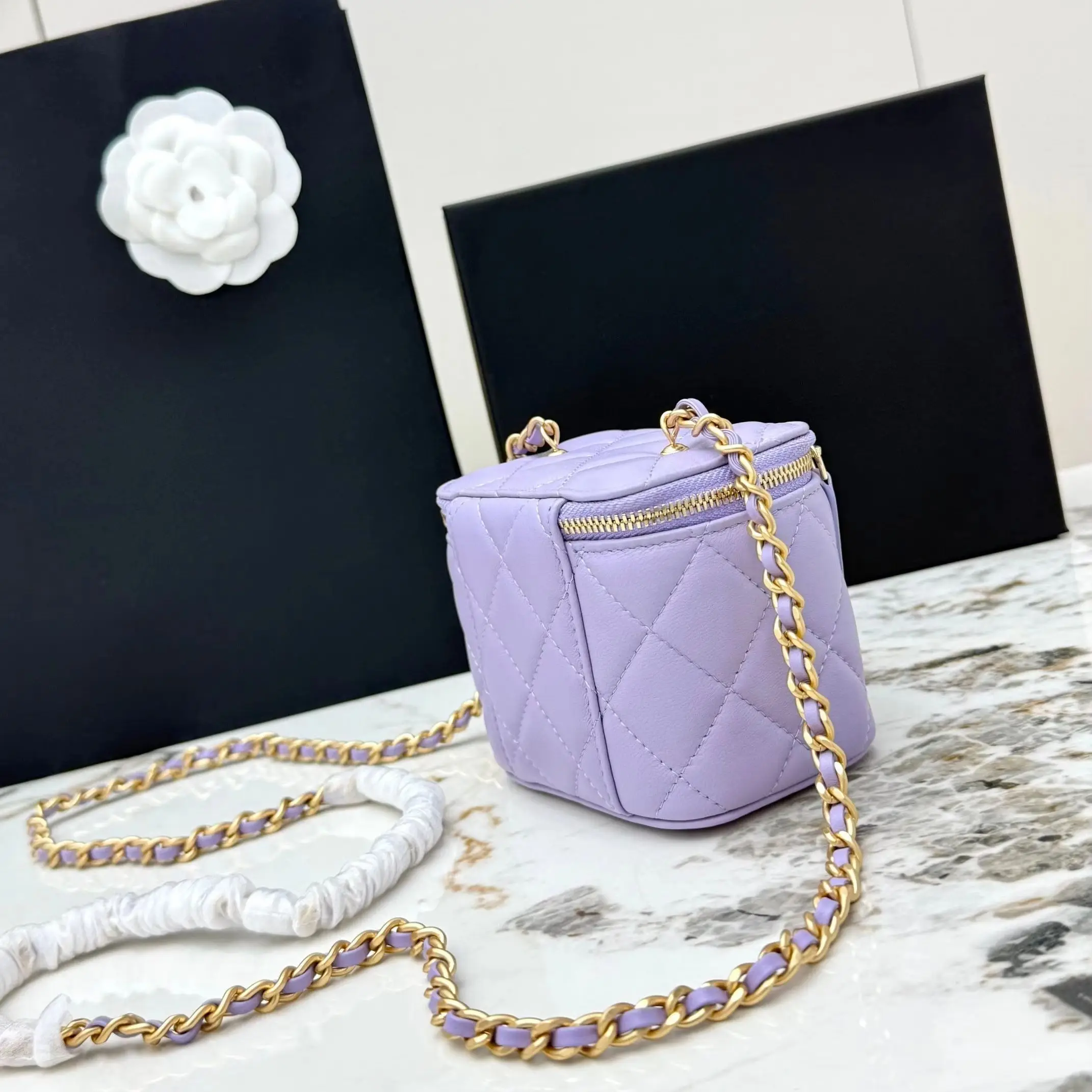 Lavender lambskin quilted mini vanity box bag with double gold zipper pulls, adjustable interwoven chain strap, gold ball accents, small women's crossbody makeup bag.