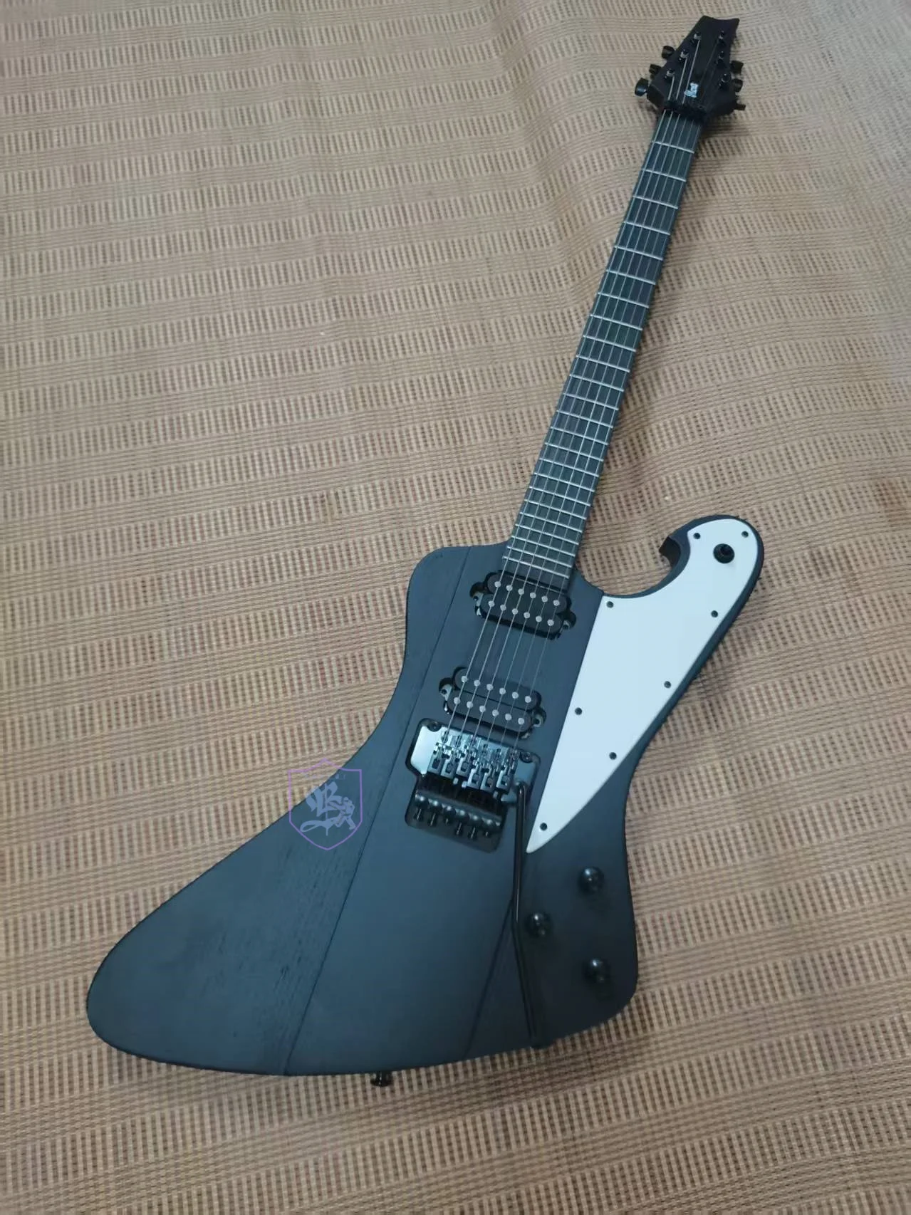 

6-string electric guitar, rosewood fingerboard, white wax wood, matte black paint, vibrato bridge, neck runs through the body