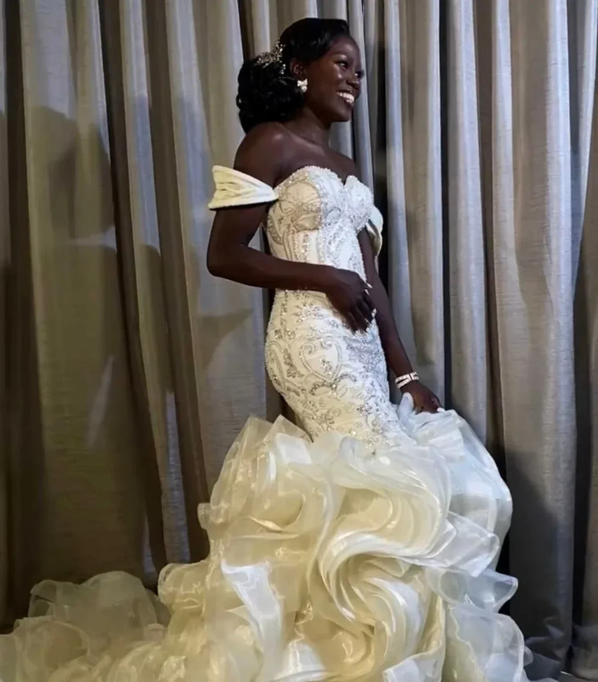 Suknia ślubna syrena z afrykańskimi, błyszczącymi perłami, z odkrytymi ramionami i kaskadowymi falbanami.