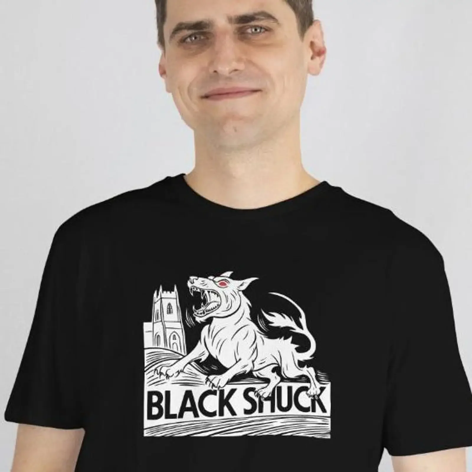 Puede incluir una camiseta negra con gráfico blanco de un perro mordedor con ojos rojos y la inscripción SHUCK debajo, estilo vintage lavado.