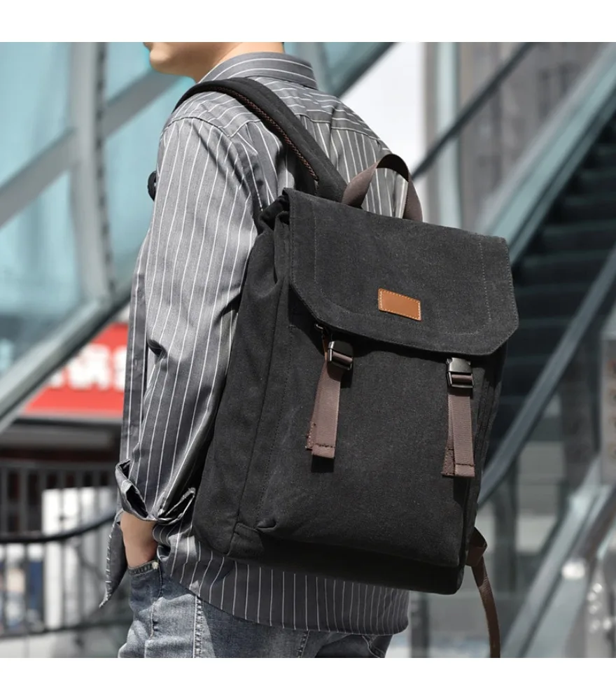 Black washed canvas flap backpack small brown leather front label dual brown plastic buckle straps compact vintage silhouette