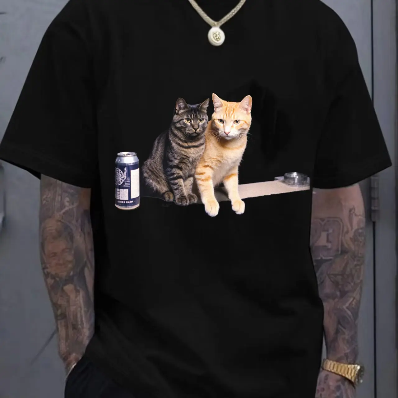 تي شيرت أبيض بتصميم مطبوع لقطط تابي باللون الرمادي الداكن والبرتقالي الفاتح جنبًا إلى جنب، علبة مشروبات داكنة على اليسار، موزع شريط #1