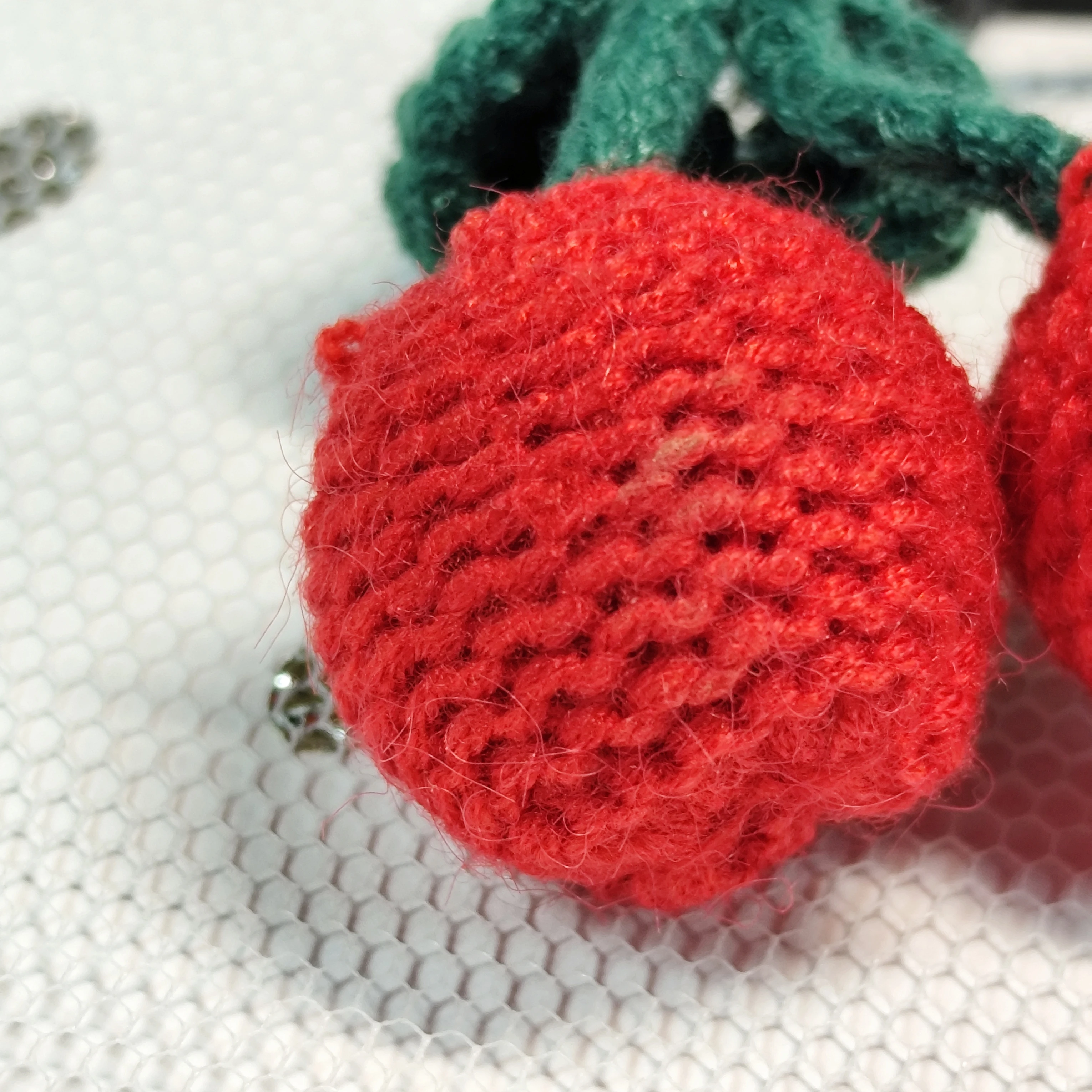 This handmade crochet cherry keychain, with vivid red cherries and green stems, is a cute accessory.