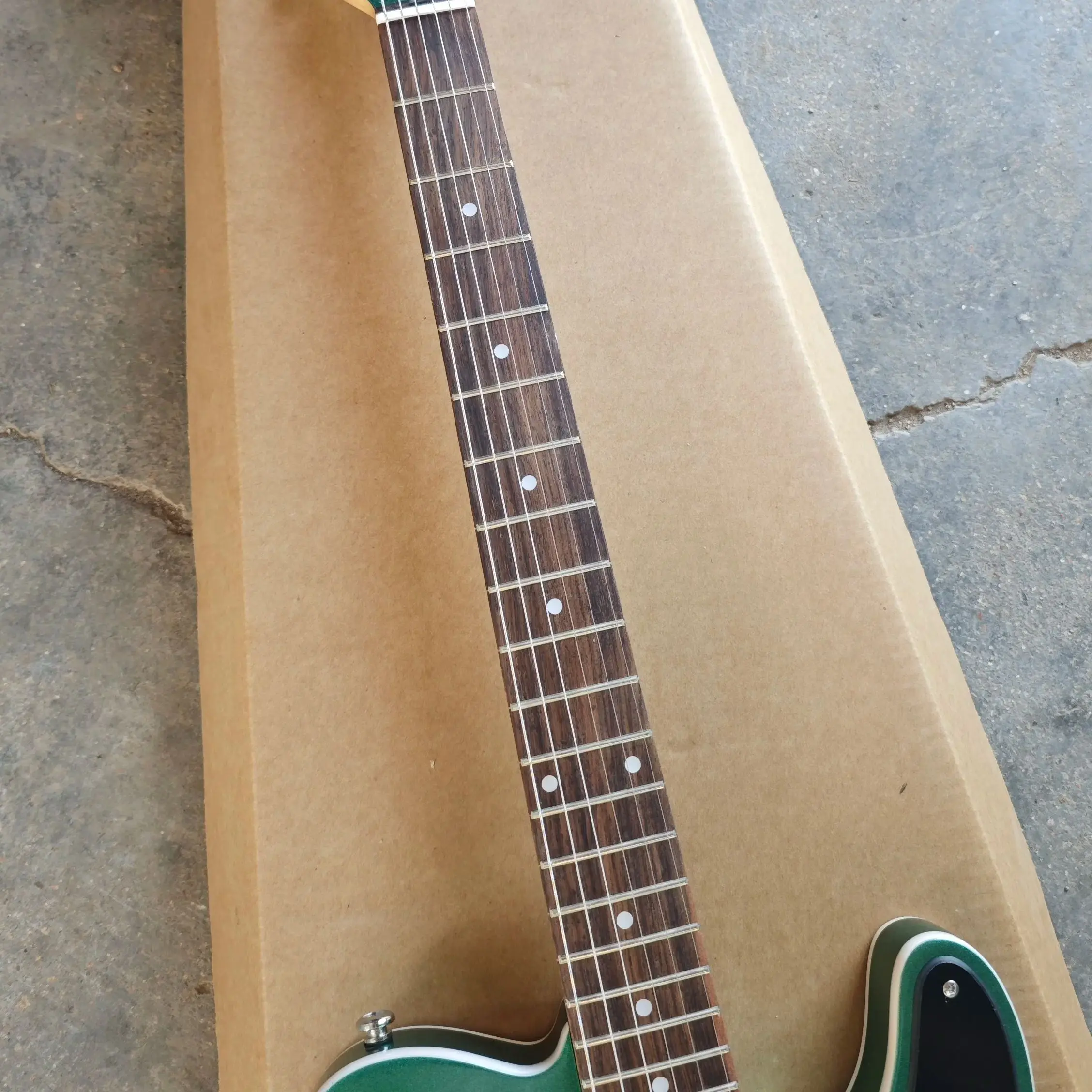 Six string electric guitar with white edging, green silver powder paint finish, black protective plate