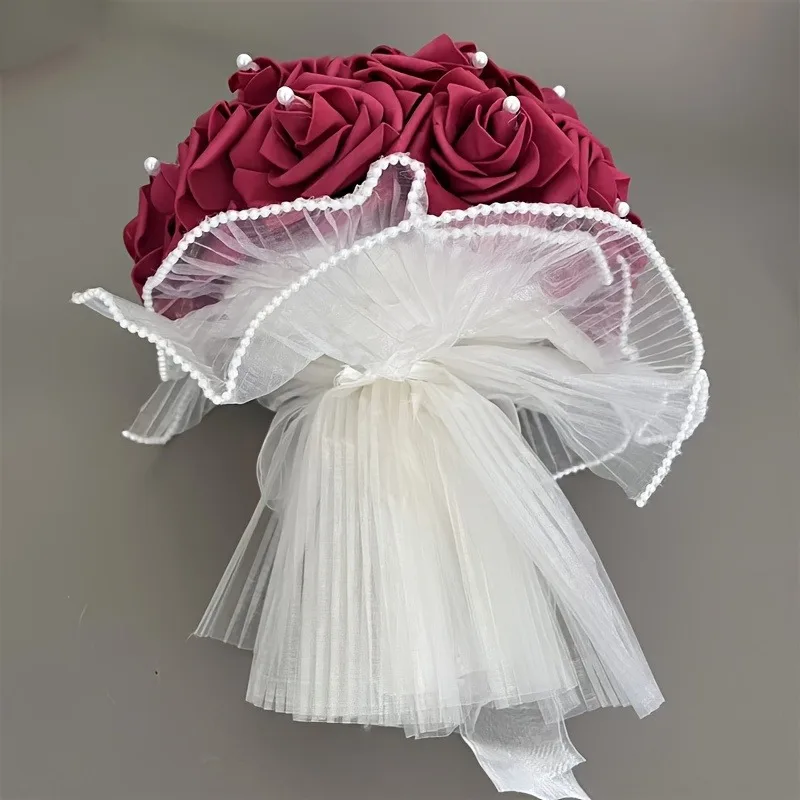 Une robe de mariée ornée de belles perles et captivantes, entourée de bouquets artificiels en forme de rose tenu dans les mains