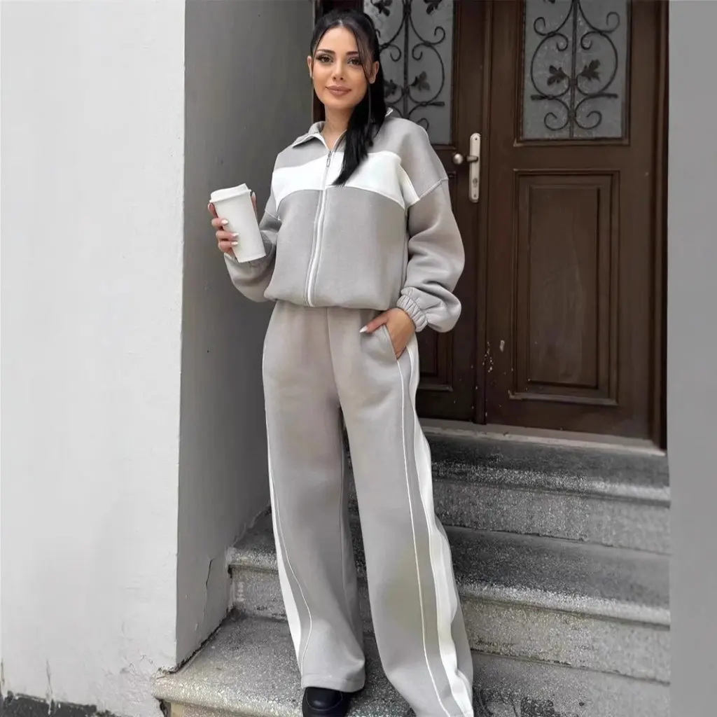 Damski zestaw w stylu casual streetwear: bluzka z wysokim kołnierzem i zamkiem błyskawicznym oraz proste spodnie w kontrastowe paski, dwuczęściowy komplet.