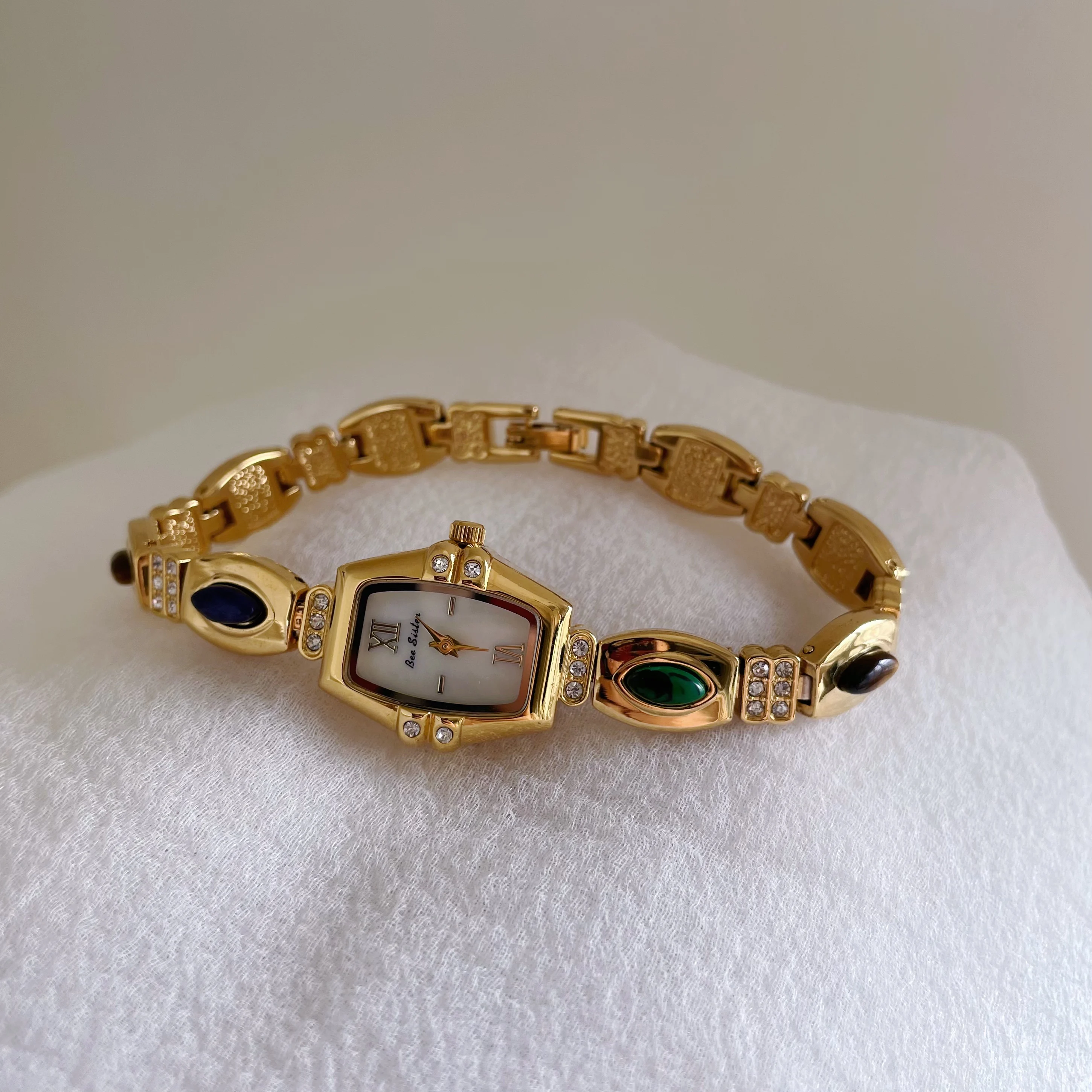 Vintage-style women's watch with colorful gemstones, tonneau-shaped dial, bracelet style, quartz wristwatch, women's accessory.