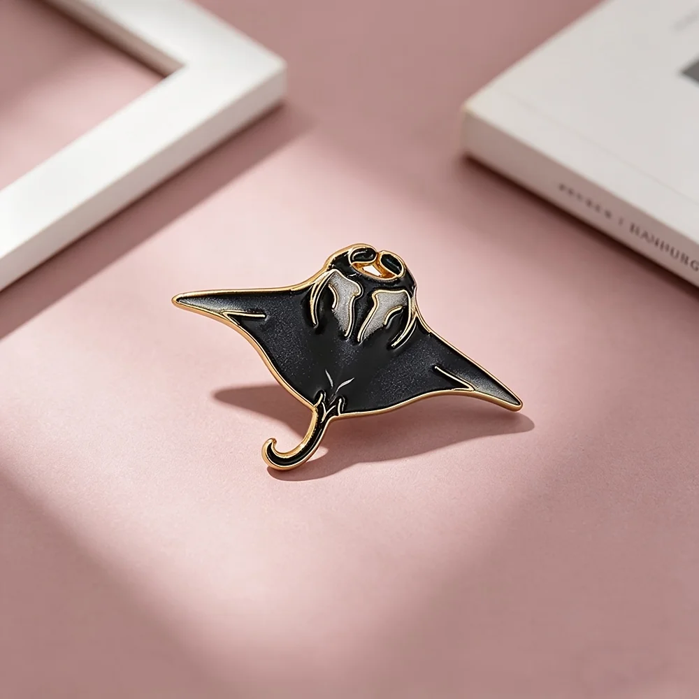 A single black and gold manta ray enamel brooch—a marine-themed accessory that pairs perfectly with denim jackets and backpacks