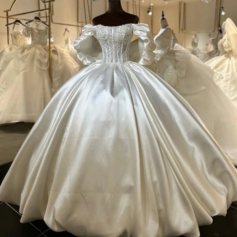 

Свадебное платье из атласа цвета слоновой кости с аппликациями, вырезом «сердечко», блестящими декоративными элементами и длинным шлейфом. Свадебное платье на заказ.