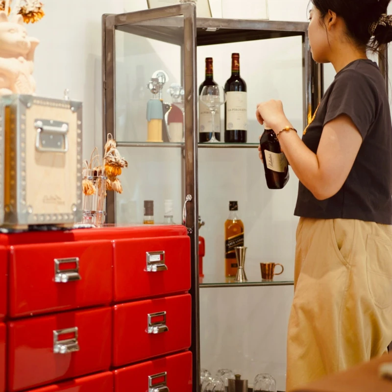 

The corner of large triangular glass display case is against wall, and display case holds wine.