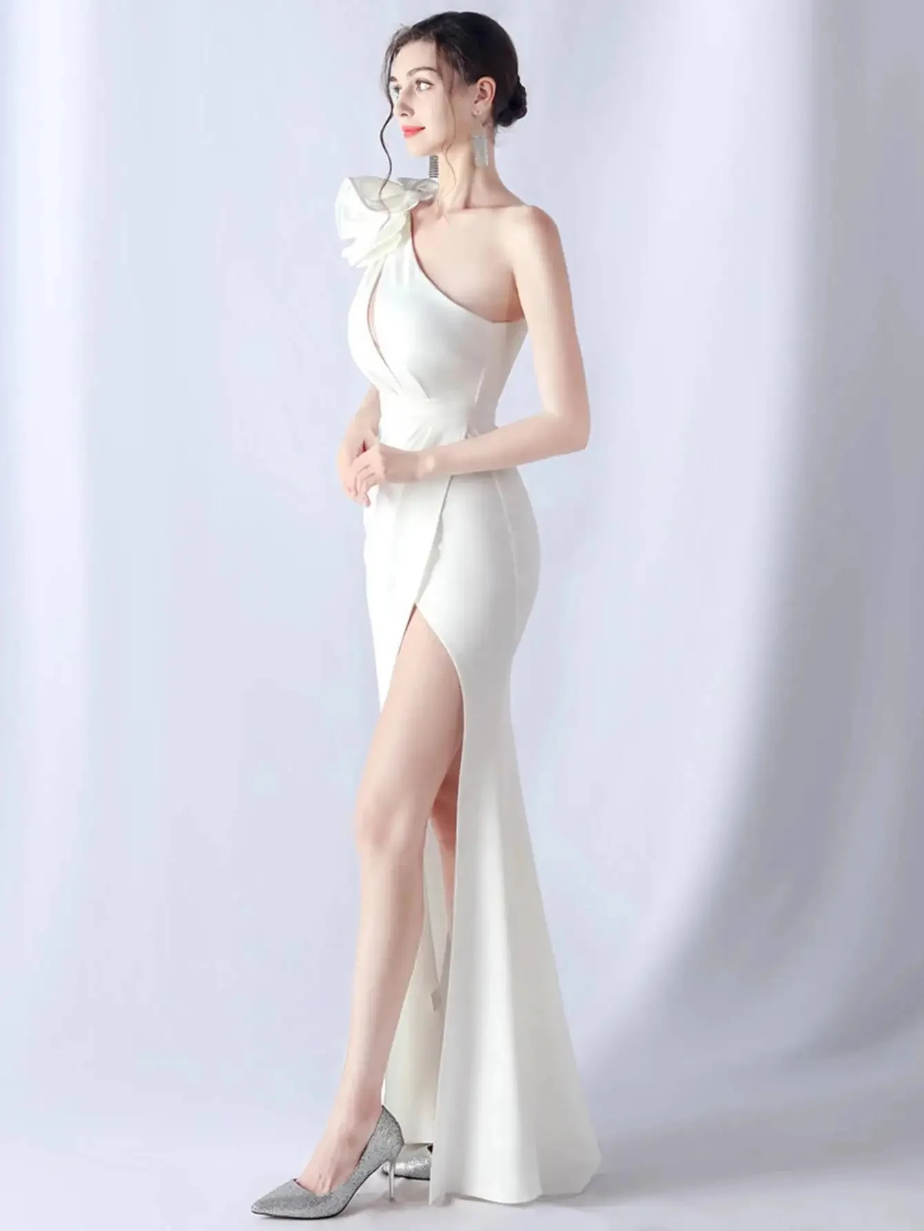 Bright solid one-shoulder floor-length gown decorated with delicate small flowers on shoulder. Fitted cut outlines body curves,