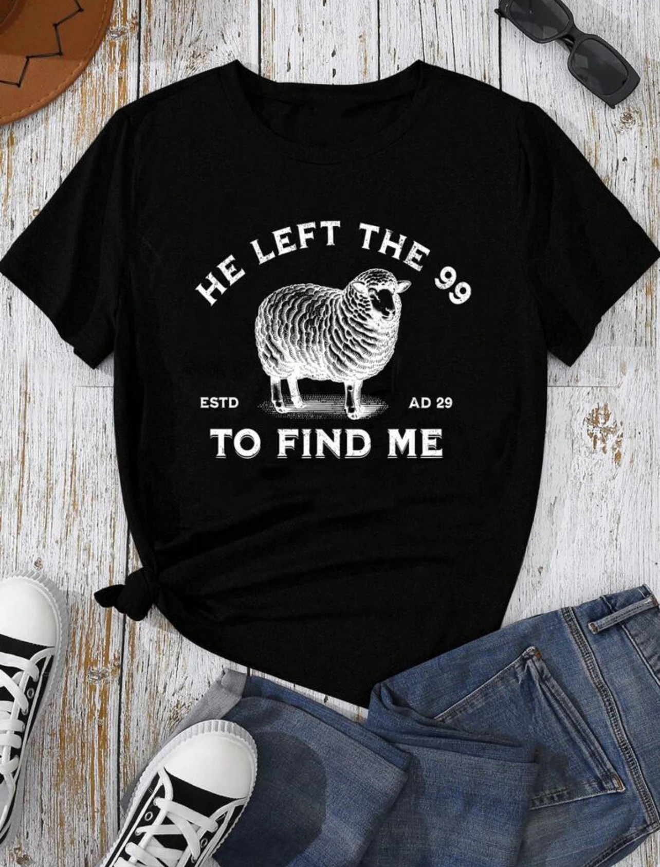 

The lady's short-sleeved round-neck casual shirt features the letters "HE LEFT THE 99 TO FIND ME" and a pattern of sheep prints