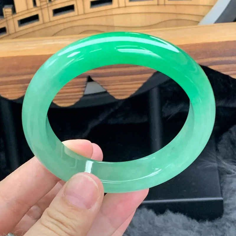 Natural Burmese jadeite bracelet with a light green hue featuring a large circular design and a smooth icy texture