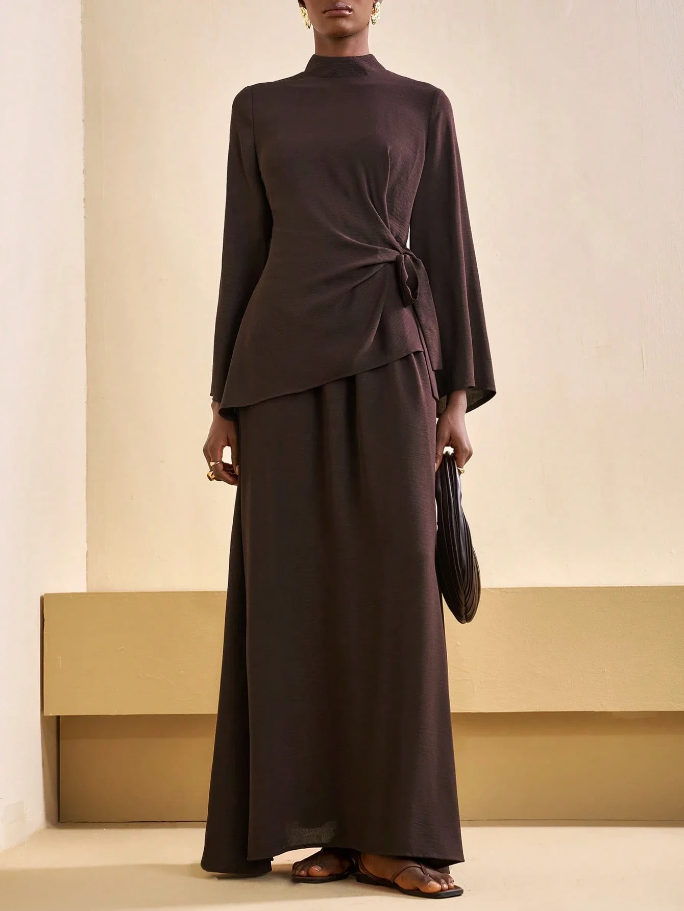 

Коричневый скромный комплект из двух предметов: рубашка с завязками на талии и асимметричным подолом, а также свободная длинная юбка А-силуэта.