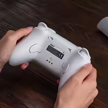 Mãos segurando um controle 8BitDo Ultimate 2 branco pela parte traseira