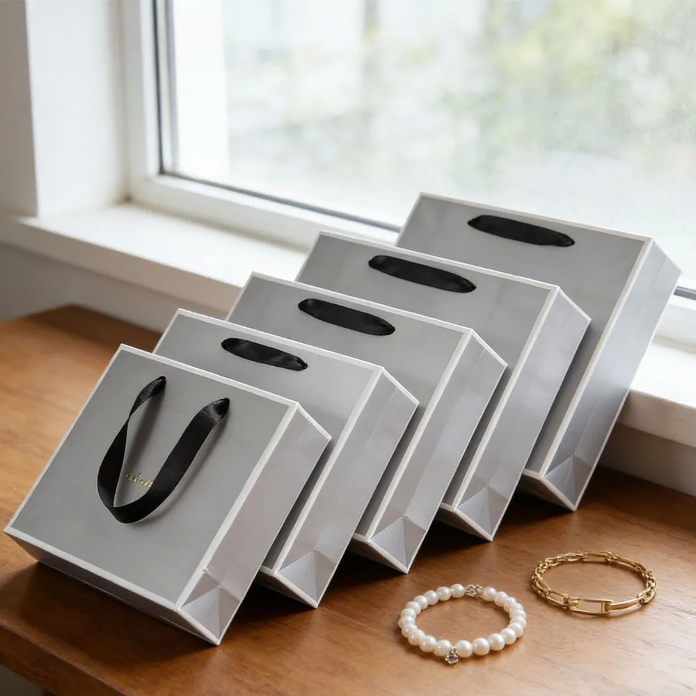 

Подарочная сумка-тоут из дизайнерской бумаги с логотипом на заказ, серебристыми ручками-лентами, для ювелирных изделий, косметики, одежды и других товаров.