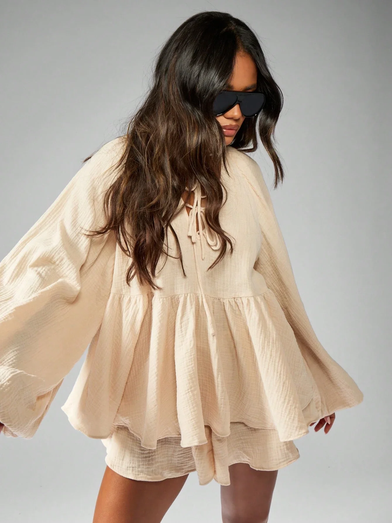 

Богемный комплект из двух предметов: блузка с рукавами-баллонами и завязками спереди, а также свободные шорты в тон.