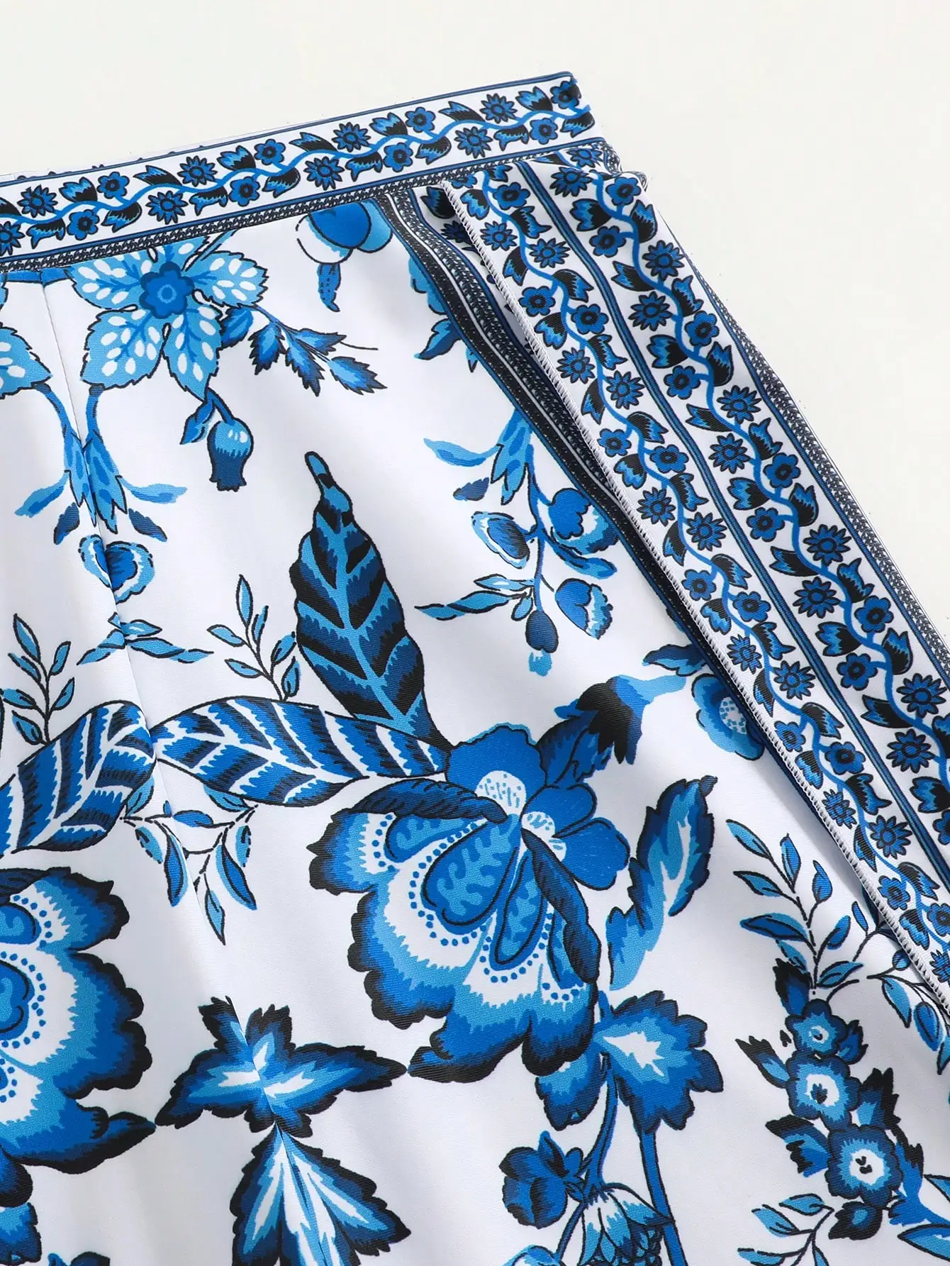 

Синий пляжный комплект из двух предметов: накидка с цветочным принтом и завязками спереди, а также широкие брюки с высоким разрезом.