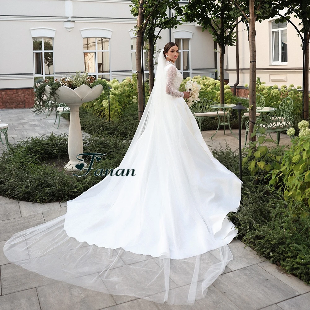 Suknia ślubna z białej koronki z dekoltem w kształcie litery O, z iluzorycznymi, długimi rękawami, trenem Watteau, długości do podłogi, o kroju syreny.