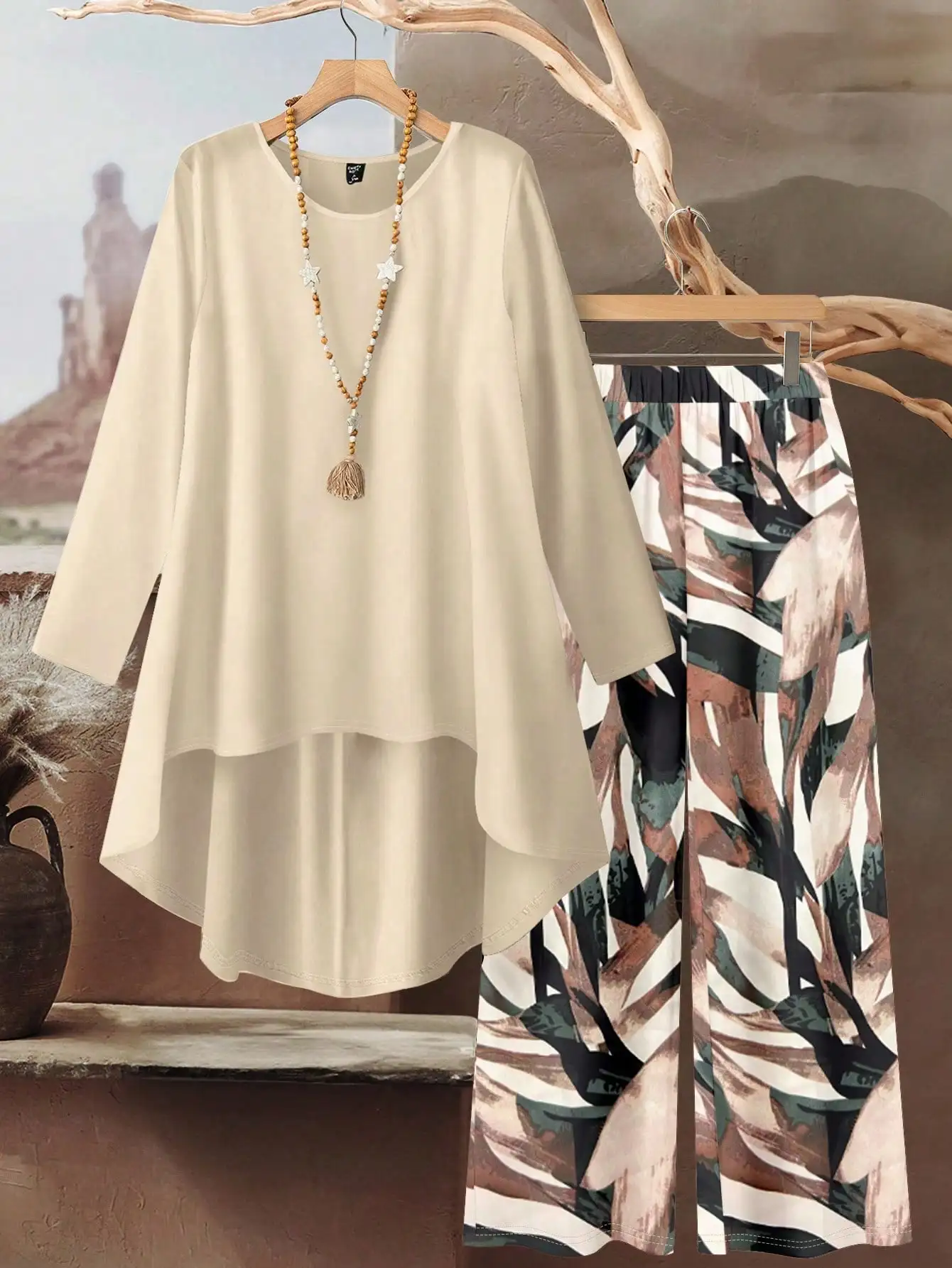 

Кремовый комплект: топ с длинными рукавами и асимметричным подолом, брюки с широкими штанинами и абстрактным принтом в виде листьев, свободный крой, большие размеры.