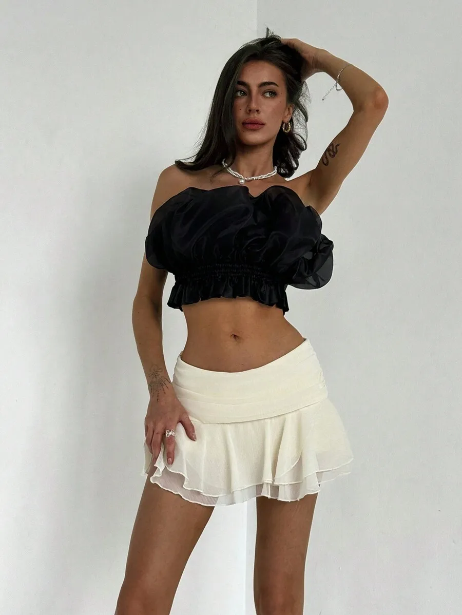 

Черный укороченный топ с пышными рукавами и драпировкой на талии, а также белая многослойная мини-юбка с рюшами.