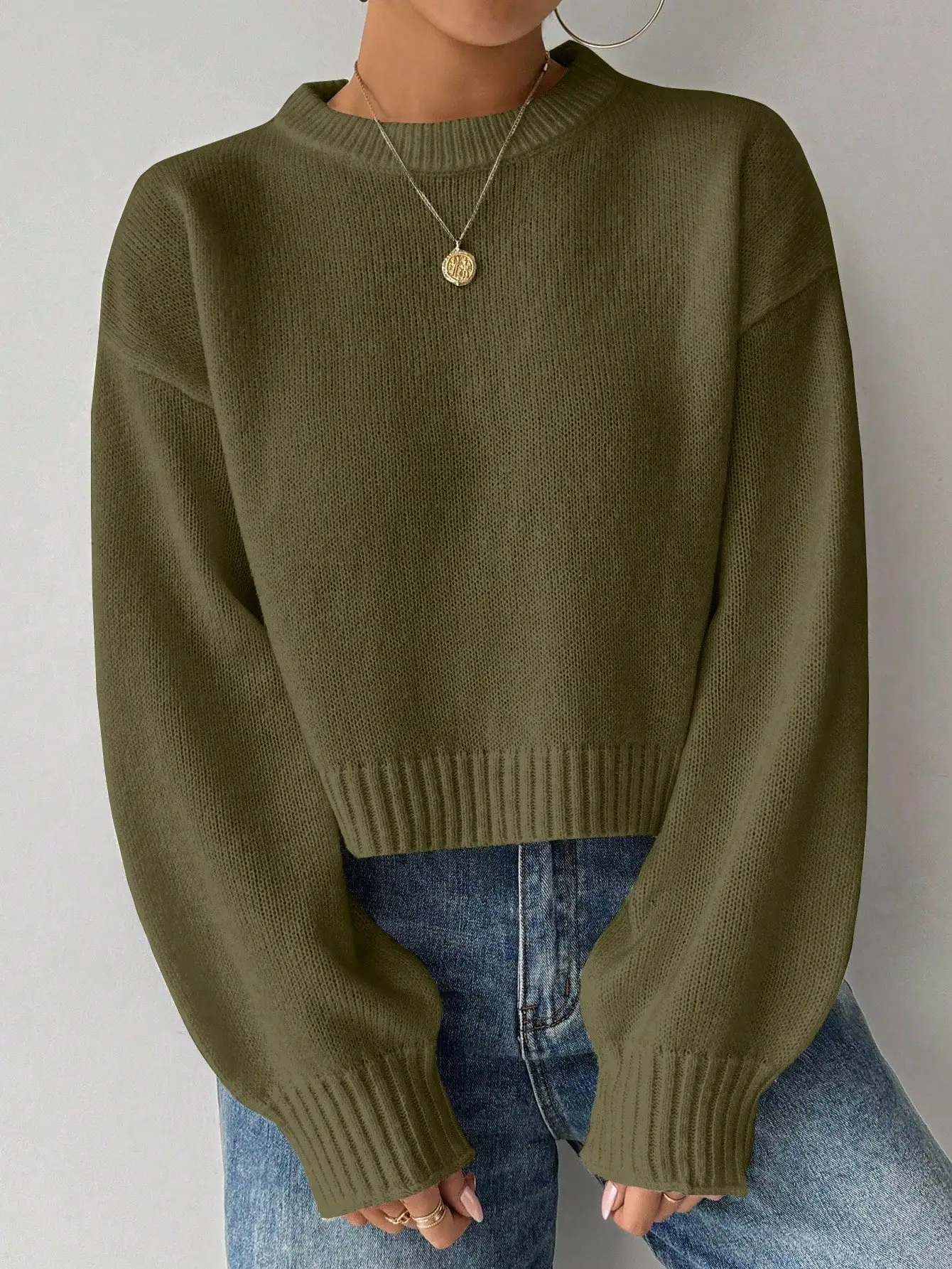Oliwkowozielony sweter damski z długim rękawem, okrągłym dekoltem, luźny krój, krótka długość.