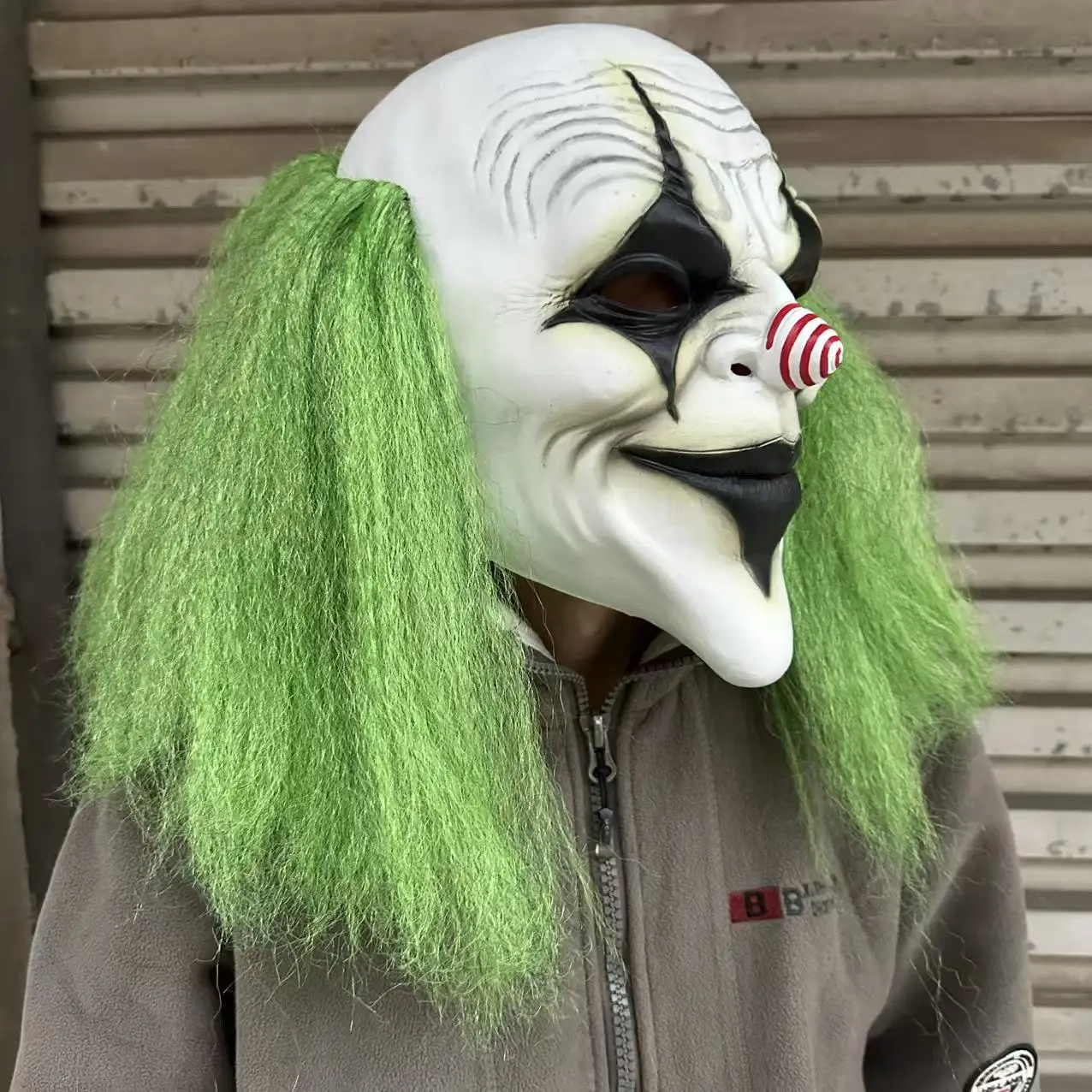 Furchteinflößender grünhaariger Clown mit Latexmaske und einer spiralförmigen rot-weißen Nase. Geeignet für Halloween-Kostümparty-Requisiten – Detail 4