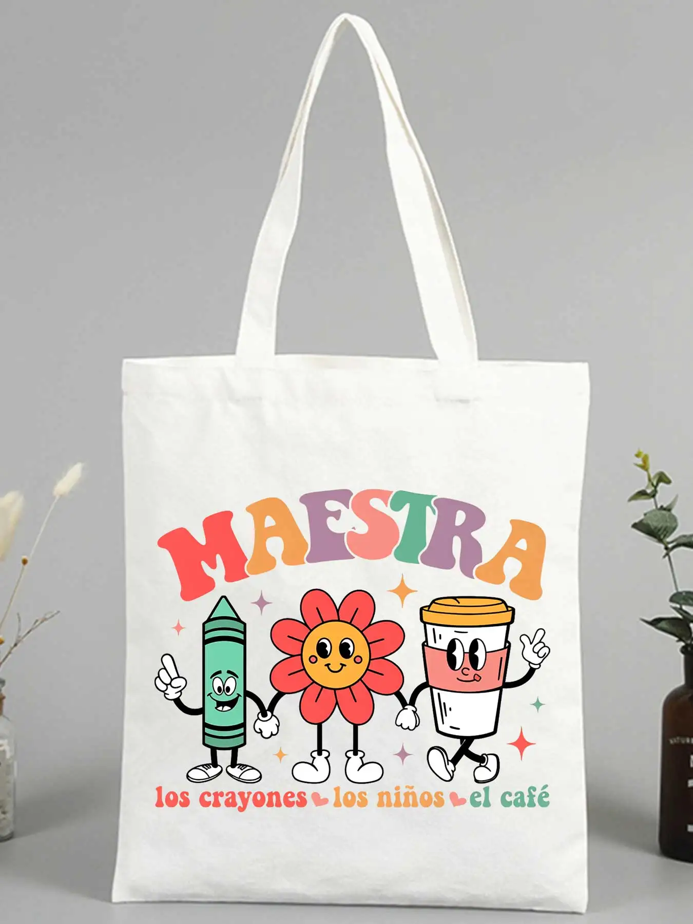 Teacher's canvas tote bag with crayon, flower, and coffee cup graphics, perfect for school use and daily errands