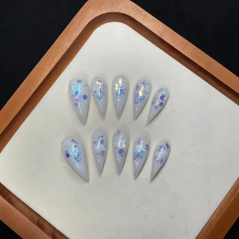 10PCS of white lacquered dagger-shaped fake nails, adorned with iridescent blue and purple sequins, with pointed tips
