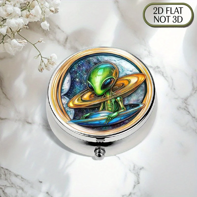 Single-piece, flat, portable, round metal pill box, featuring a blue alien flying on a spaceship, with a shiny, colorful glass lid, perfect for organizing medication and vitamins during travel