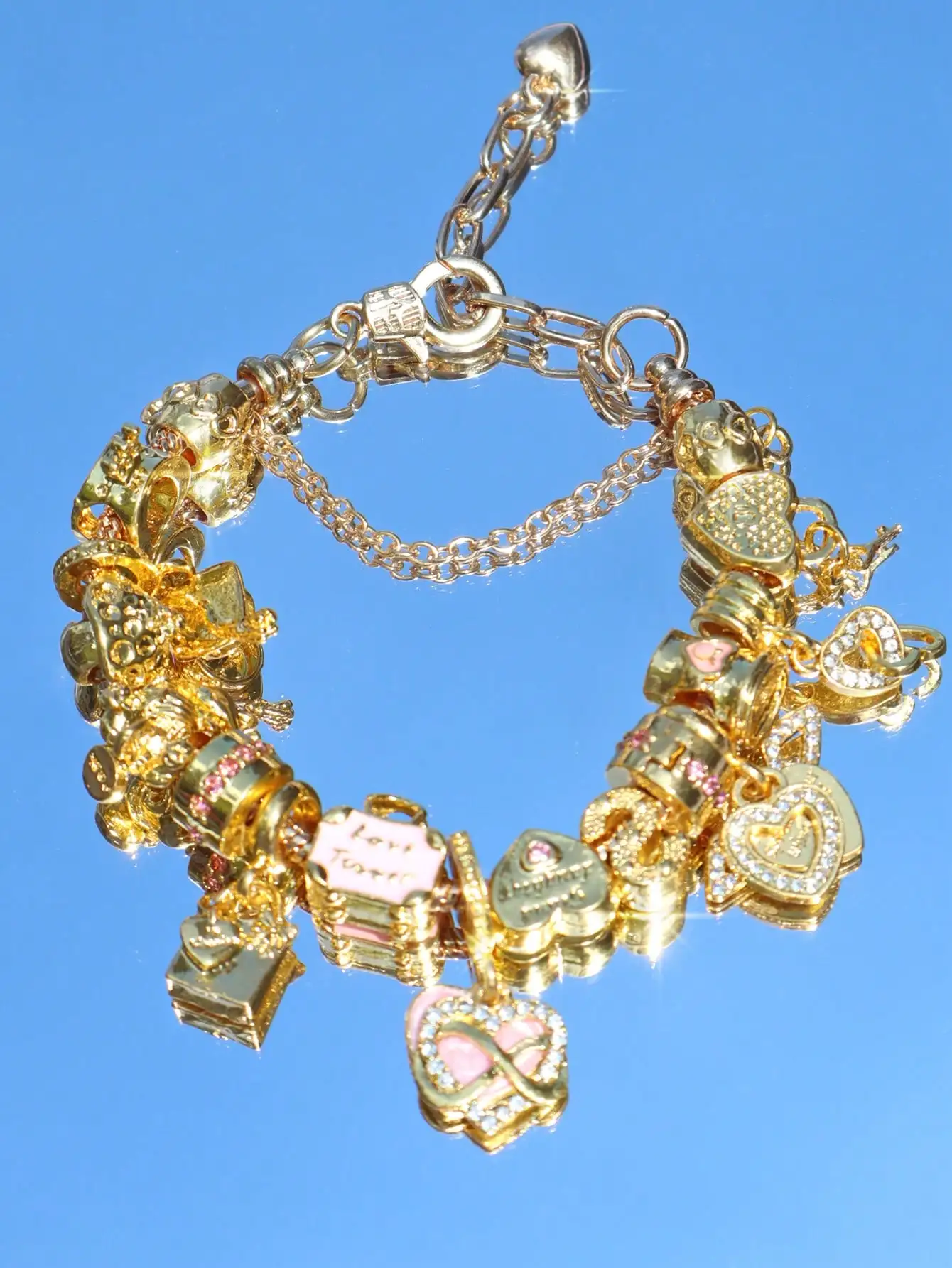 

Браслет с подвесками золотистого цвета, украшенный подвесками в виде сердца, символа бесконечности и коробочки, с акцентами из розовой эмали.