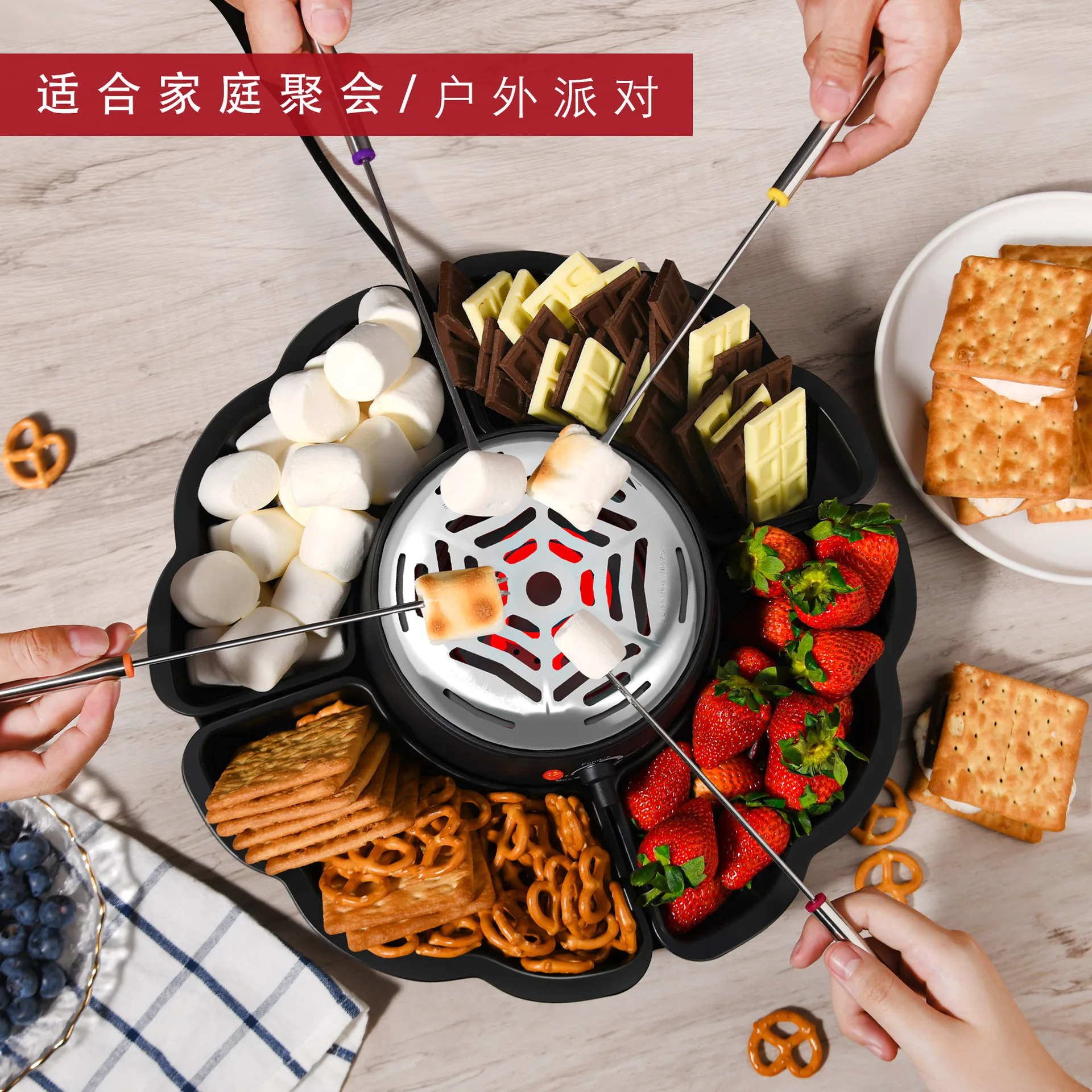 صانع سموريس الكهربائي على سطح الطاولة مع صواني لمفرقعات جراهام والشوكولاتة والمارشميلو واللوازم الليلية للفيلم